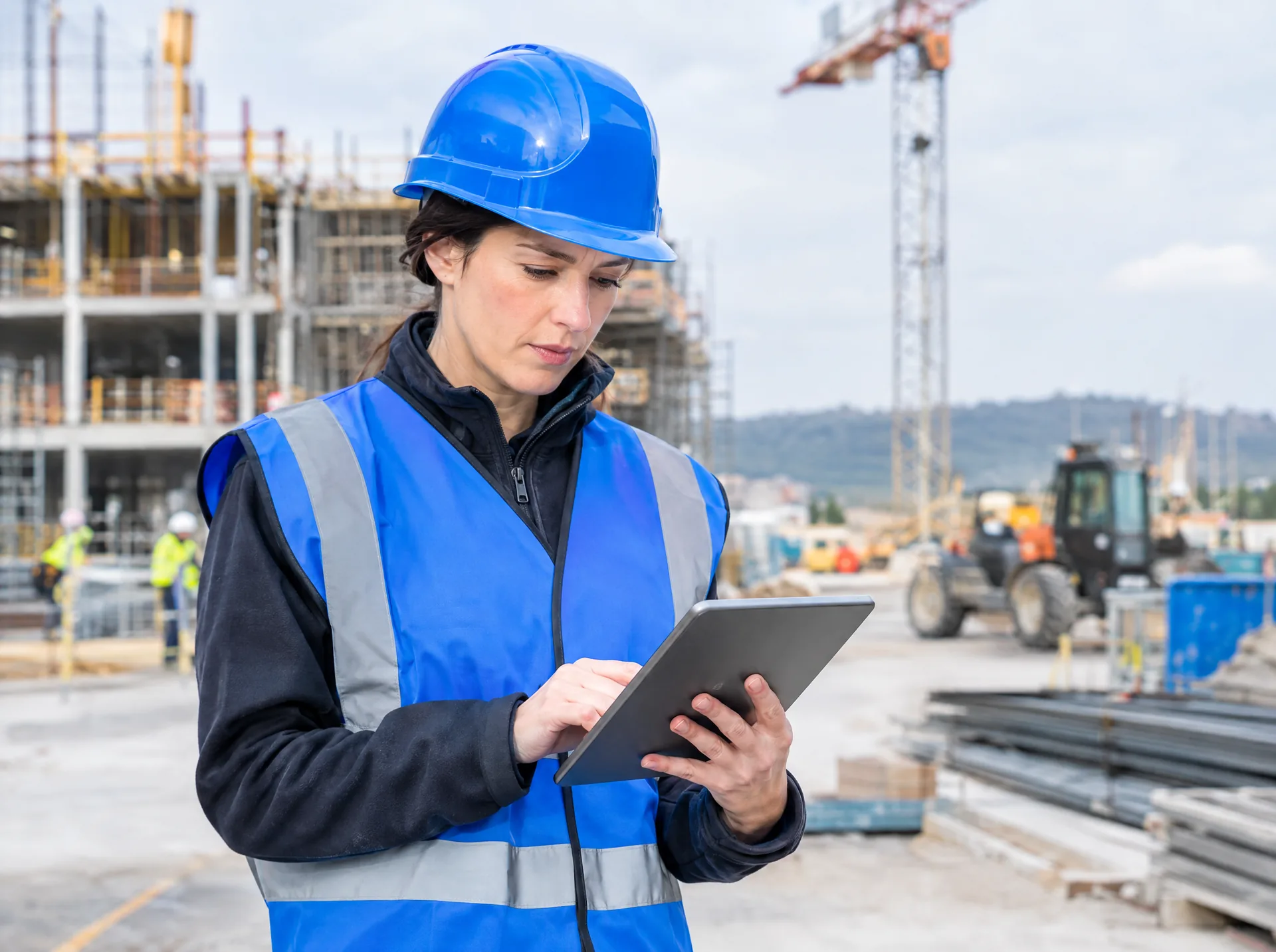 Site engineer in a hard hat with a tablet on a construction site