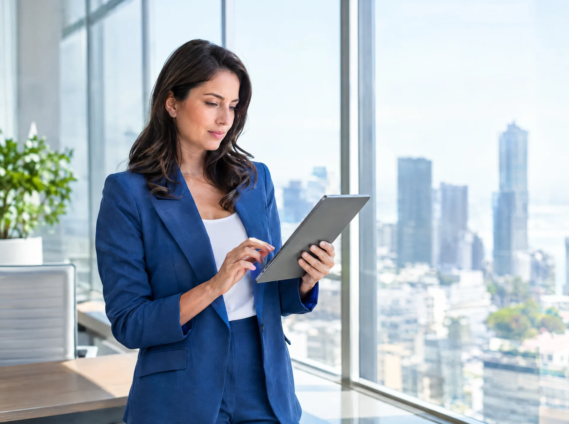 Banking professional with a tablet by an office window over the city