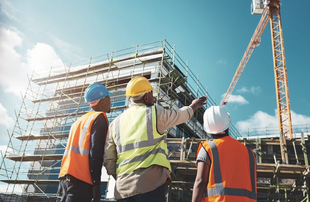 Site engineers reviewing progress beneath a construction crane