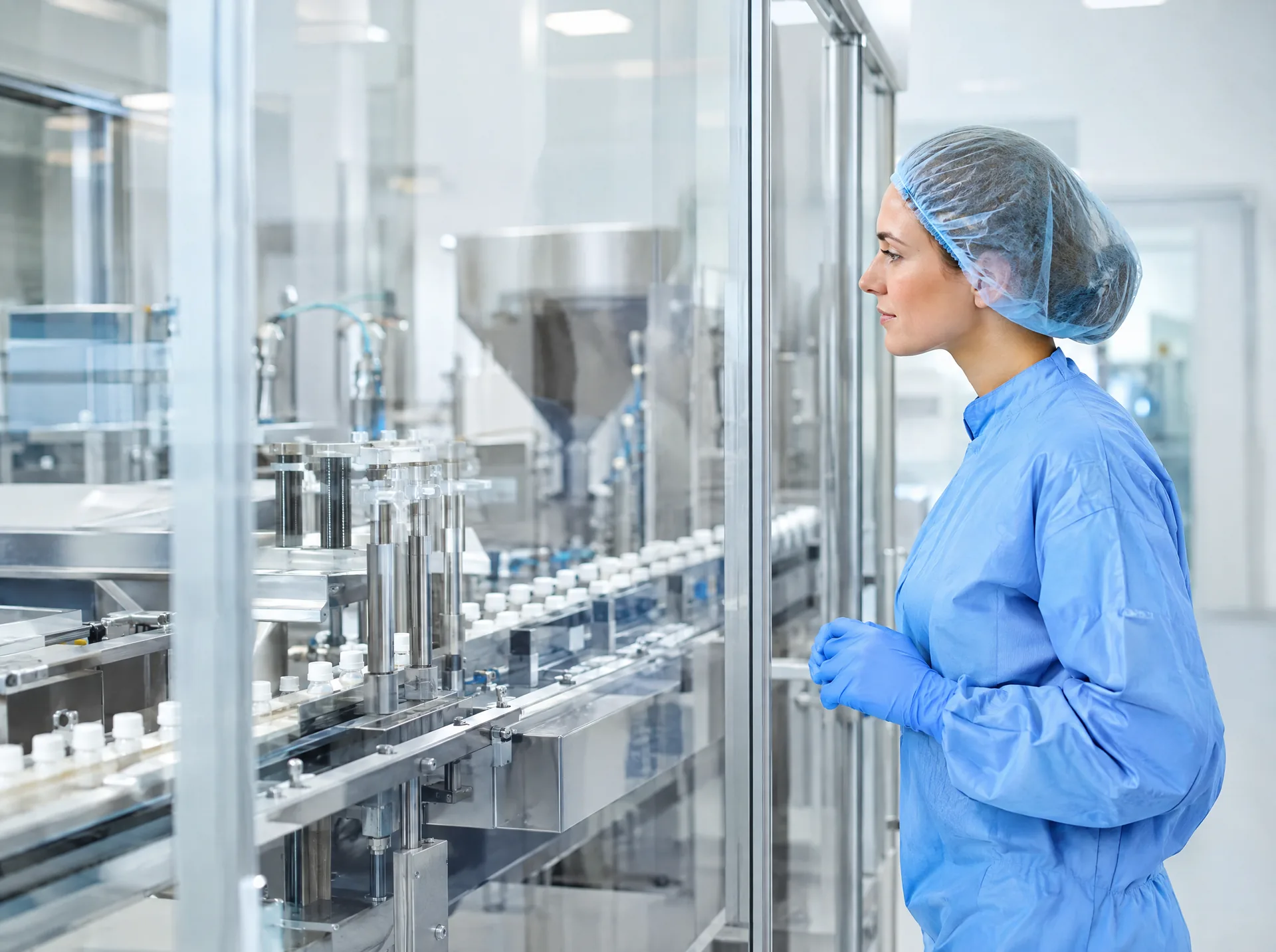 Technician in a hairnet beside a pharmaceutical filling line