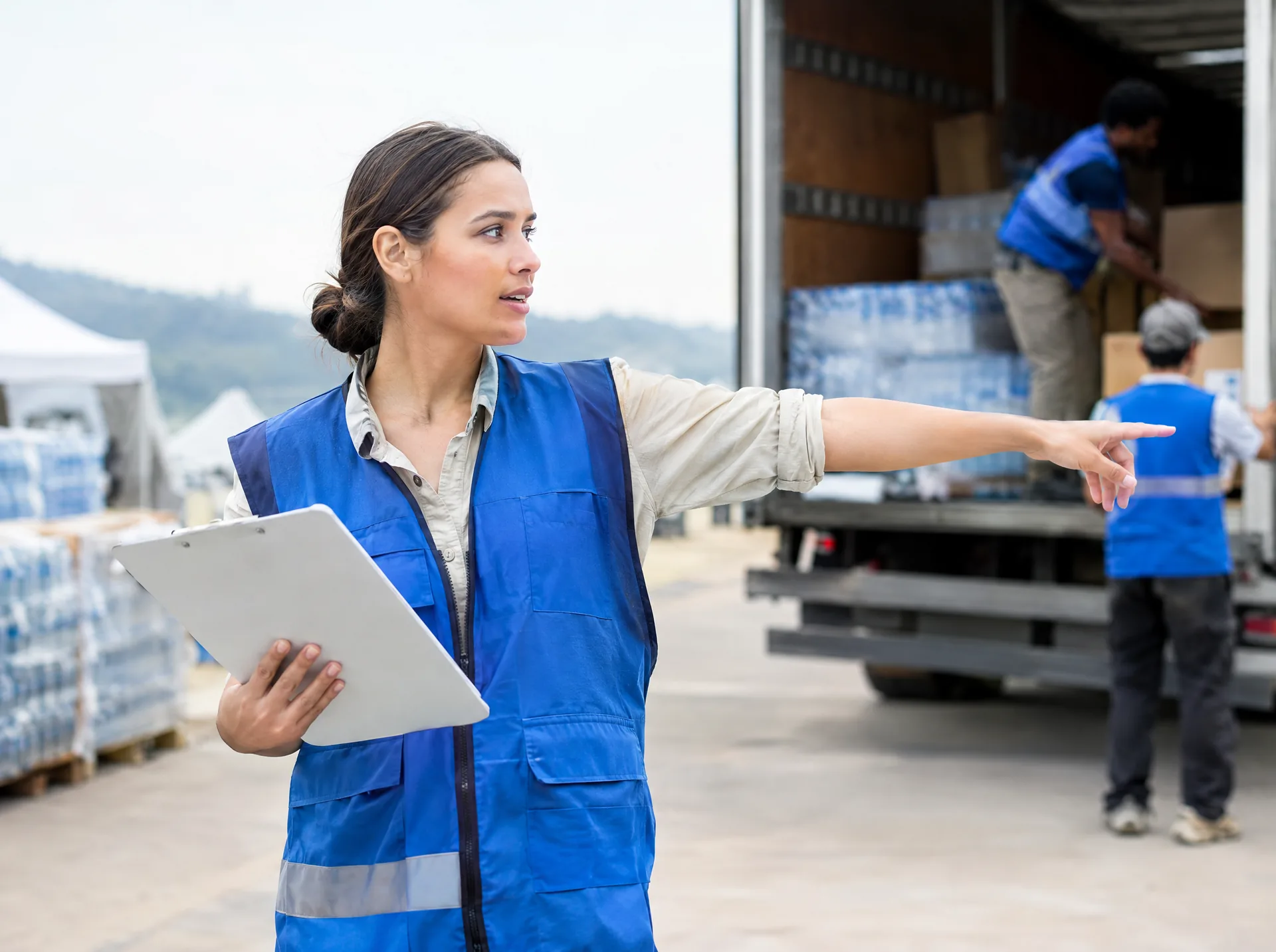 Aid worker with a clipboard directing a relief supply truck