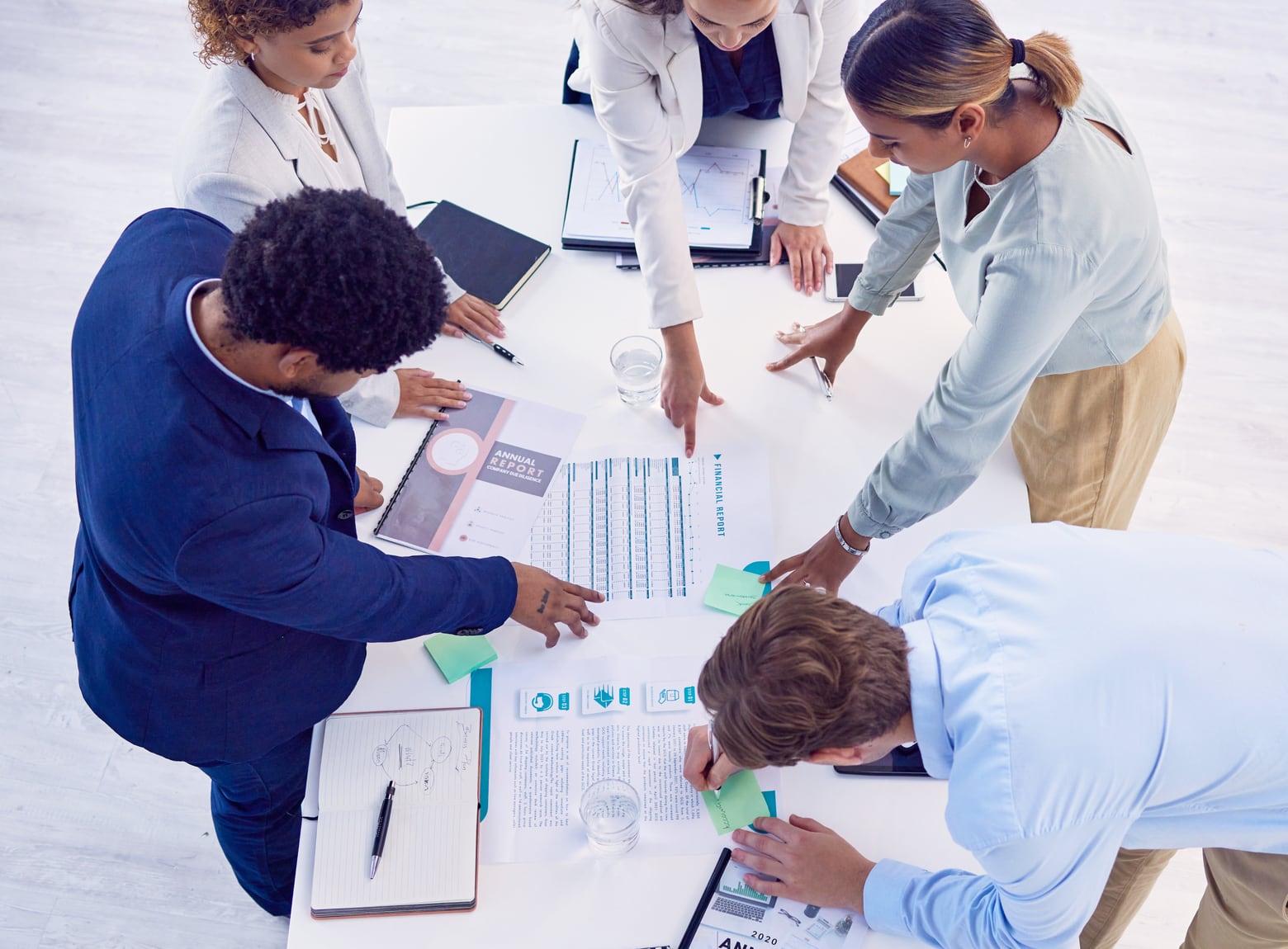 A team reviewing reports and charts around a table, seen from above
